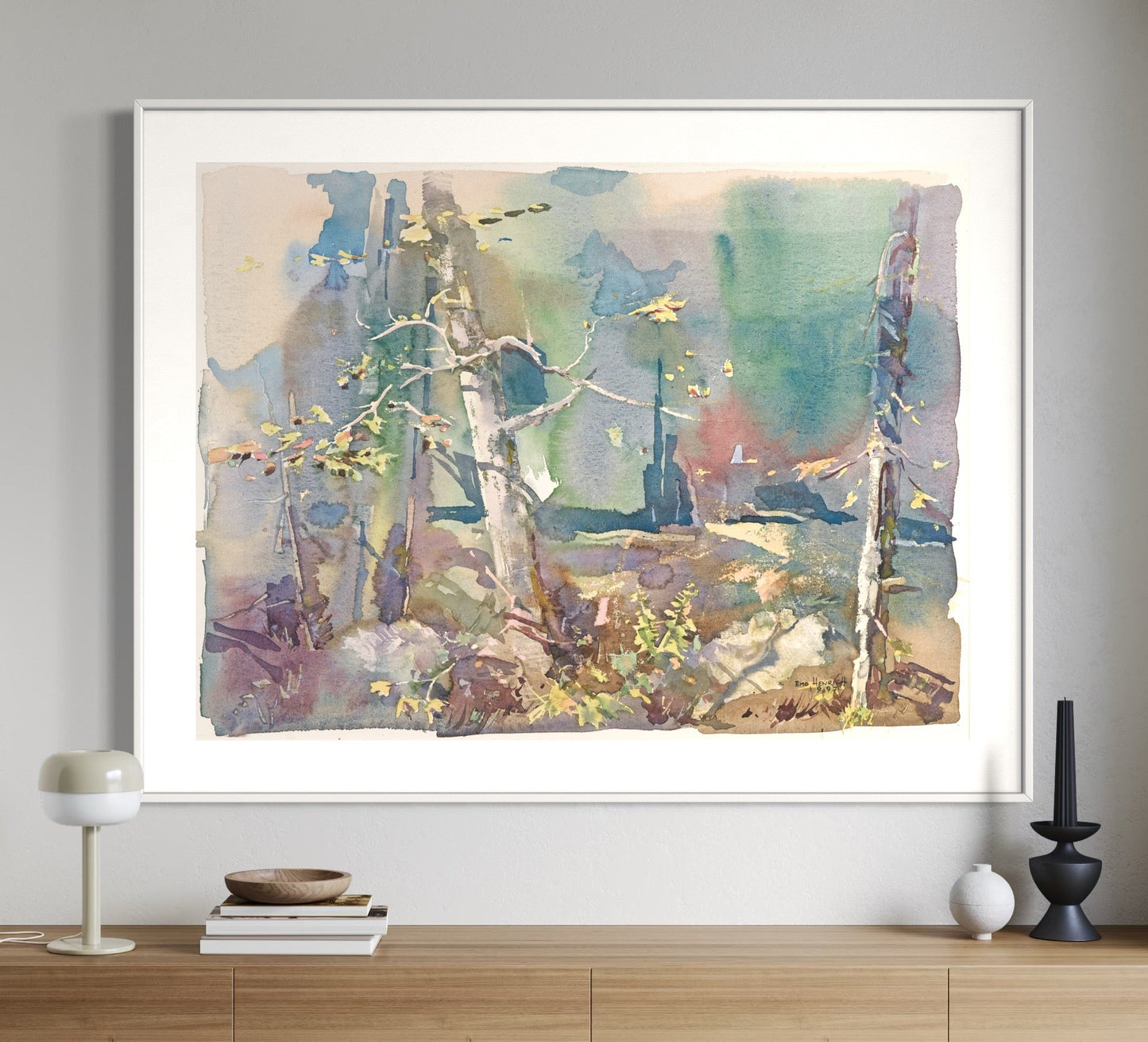 A framed watercolor painting depicting a colorful forest scene hang on a wall above a wooden console table.