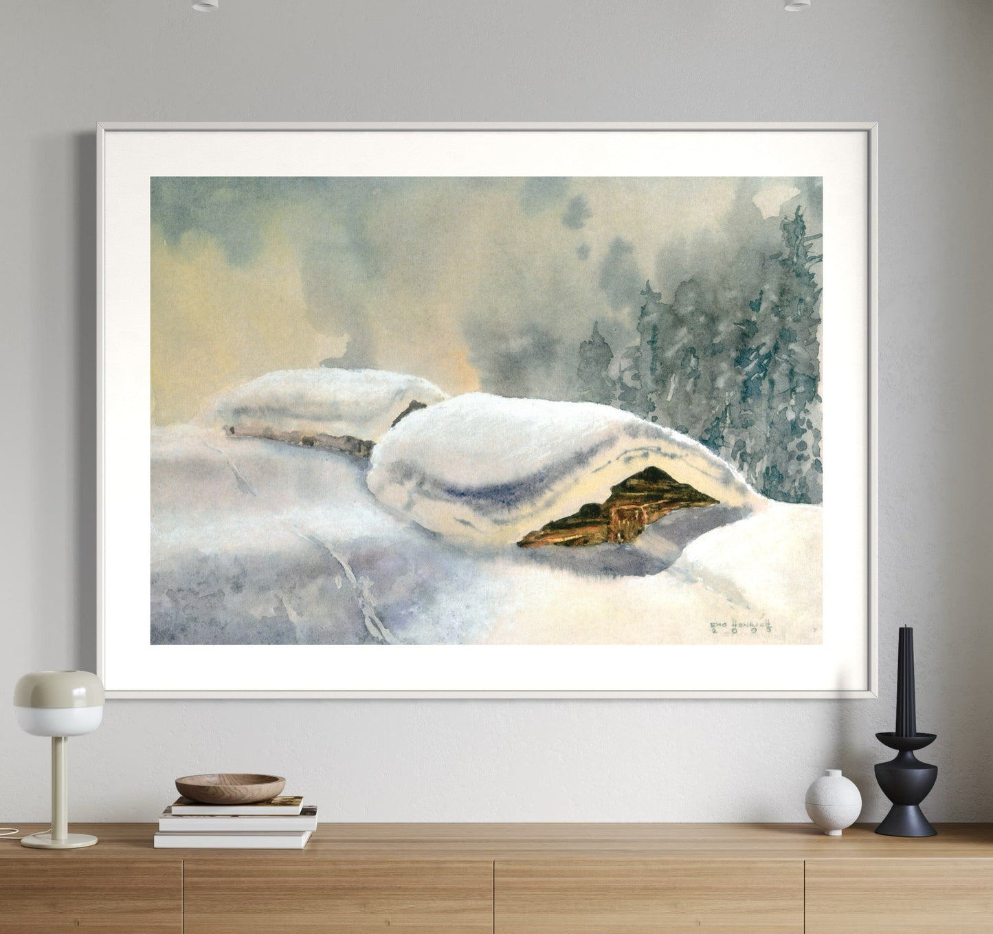 A framed watercolor painting of snowy huts displayed on a wall above a console table.
